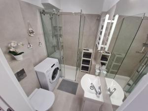 Gdynia Główna Apartament في غدينيا: حمام مع حوض استحمام وغسالة ملابس