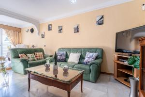 sala de estar con 2 sofás verdes y TV en MalagaSuite Sotomar Apartment, en Torremolinos