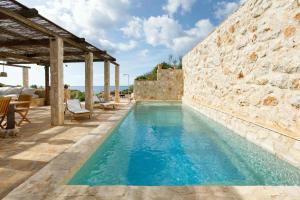 a pool with a stone wall and blue water at Villa Vito in Hvar