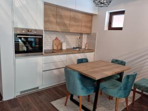 Garnet Star Apartments, Kopaonik, apartman broj 4 في كوباونيك: مطبخ مع طاولة خشبية وكراسي زرقاء
