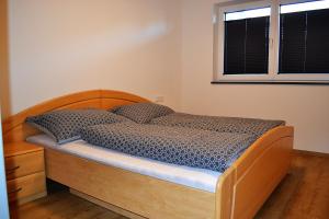 Schlafzimmer mit einem Bett mit einem Holzrahmen und einem Fenster in der Unterkunft Appartement Diana in Sankt Veit im Pongau