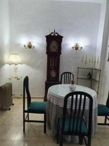 une table et des chaises avec une horloge grand-père dans la chambre dans l'établissement Carmen de la Sultana, à Grenade