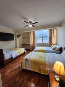 um quarto de hotel com 2 camas e uma ventoinha de tecto em HOTEL WISMONT em La Merced