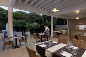 a woman standing in a restaurant with tables and chairs at VOI Daniela Essentia in Conca Specchiulla