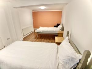 2 bedden in een kleine kamer met witte lakens bij Richmond HOUSE in Slough