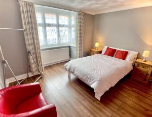 1 dormitorio con 1 cama y 1 silla roja en Richmond HOUSE, en Slough