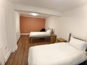 a hotel room with two beds and a desk at Richmond HOUSE in Slough