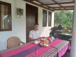 a man sitting at a table with food on it at Happy Living Weligama in Weligama +31 photos