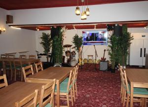 a restaurant with wooden tables and chairs and a tv at Churchill Hotel & Nagawa Restaurant in Coventry