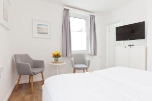 a bedroom with a bed and two chairs and a table at Haus Menno Janssen - Doppelzimmer in Norderney