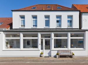 ein weißes Gebäude mit einer Bank davor in der Unterkunft Haus Menno Janssen - Doppelzimmer in Norderney