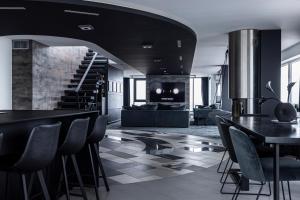 een woonkamer met zwarte tafels en stoelen en een trap bij Sky Garden Penthouse in Klaipėda