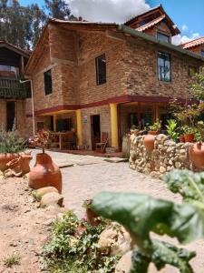 une grande maison en briques avec des vases devant elle dans l'établissement Arte sin Fronteras Hostel, à Paipa