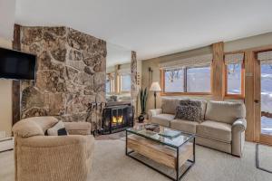sala de estar con pared de piedra y chimenea en Laurelwood Condominiums 402 en Snowmass Village