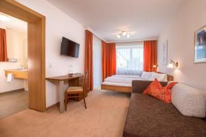 a hotel room with a couch and a bed and a desk at Garni Rösslhof in Hollersbach im Pinzgau