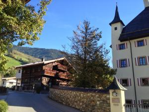 a building with a tower next to a stone wall at Geigerhaus 500 Jahre - Appt C in Stuhlfelden