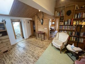 Sala de estar con silla, mesa y libros en Geigerhaus 500 Jahre - Appt C, en Stuhlfelden