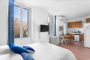 um quarto branco com uma cama grande e almofadas azuis em Agreeable studio with AC in le Mourillon - Dodo et Tartine em Toulon