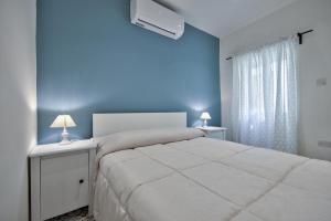 a bedroom with a white bed and a blue wall at Borgo Apartments 1 & 2 Bedroom Self-Catering Units in Central Valletta in Valletta +56 photos