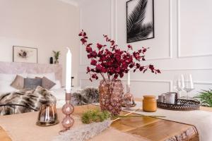 une table avec un vase et des fleurs rouges sur elle dans l'établissement 90sqm 2BR Biz LOFT - 5min Central Station, à Berlin