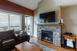 a living room with a fireplace with a flat screen tv at Trappers Crossing 22 in Big White