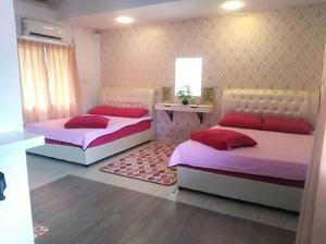 two beds in a room with pink and red pillows at Challet Baitul Hanan with Private Pool near KLIA in Sepang