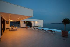 une maison avec une piscine et une terrasse avec des chaises dans l'établissement Villa Garma Beachfront - 3 Bedroom villa - Stunning Sea Views - Gym - Private Pier, à Potirna
