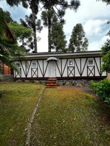 een wit gebouw met een deur in een tuin bij Apartamento Foss in Gramado