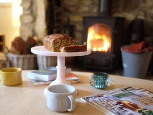 a cake on a plate on a table with a coffee mug at Little Brook Cottage in Hebden