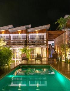 a swimming pool in front of a building at night at Pousada Rosa Tropicalia in Praia do Rosa