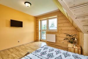a bedroom with a bed and a tv on a wall at By the River in Chochołów