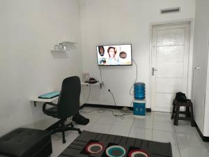ein Wohnzimmer mit einem Stuhl und einem TV an der Wand in der Unterkunft Giri Home & Travel in Ciwidey