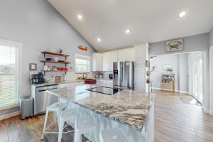 a kitchen with white cabinets and a marble counter top at Packsaddle Beach House in Rockport