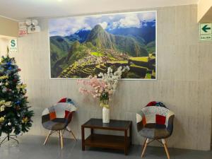 ein Weihnachtsbaum und zwei Stühle und ein Gemälde an der Wand in der Unterkunft HOTEL ESTRELLA in Lima