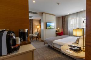 トラブゾンにあるKuhla Hotelのベッド、デスク、テレビが備わるホテルルームです。