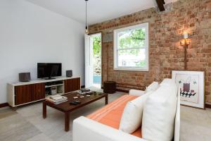 a living room with a white couch and a brick wall at Varanda a 500m da praia de Ipanema e 100m da Lagoa in Rio de Janeiro