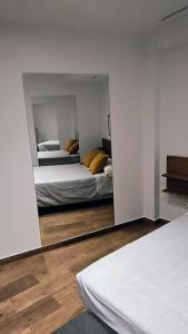 a bedroom with two beds and a mirror at apartamento Ciempozuelos II in Ciempozuelos