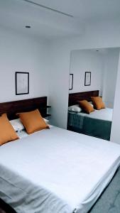 a bedroom with two beds with white sheets and orange pillows at apartamento Ciempozuelos II in Ciempozuelos