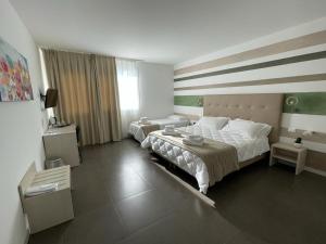 a bedroom with two beds and a large window at Hotel Grel in Chiaramonte Gulfi