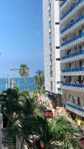 un gran edificio junto a una playa con palmeras en Apartamento Rodadero, Edificio Palanoa 308, en Santa Marta