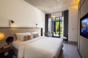 a bedroom with a large white bed and a tv at Hotel Ping Silhouette in Chiang Mai