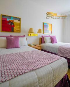 2 camas en una habitación de hotel con sábanas moradas y blancas en Hotel San Marcos Grand, en Culiacán