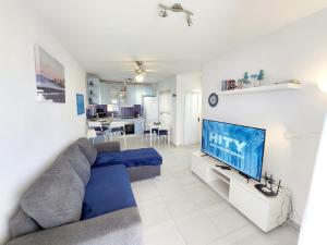 a living room with a blue couch and a tv at Brisa Marina - Vista Golf 2 - WiFi - swimming pool in Caleta De Fuste