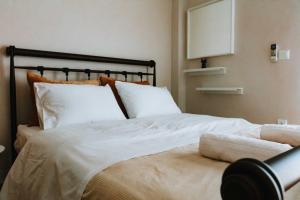 1 cama con sábanas blancas y almohadas en una habitación en 3 Bros Studio, en Chalkida