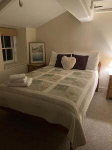 a bedroom with a large bed with a blanket at Jacobs Cottage in Port Isaac