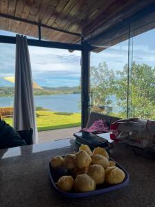 a plate of food on a table with a view of the water at Chalé Mirante, piscina, cachoeira, lago e vista espetacular in Alexânia