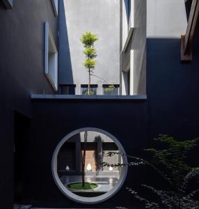 ein rundes Fenster in einem Gebäude mit einem Baum darin in der Unterkunft Hotel Ping Silhouette in Chiang Mai