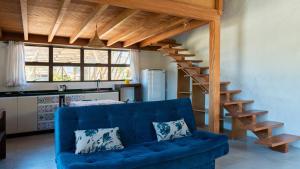 a living room with a blue couch and a staircase at Pousada Rosa Tropicalia in Praia do Rosa