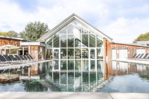 a building with a fountain in front of a pool at Clearwater 67, Ortolan Villa P in Somerford Keynes