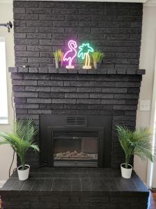 a fireplace with a flamingos neon sign and two plants at King Bed 2bed1bath Sleeps 5 Close To Town Center Downtown Beach Mayo Clinic New in Jacksonville